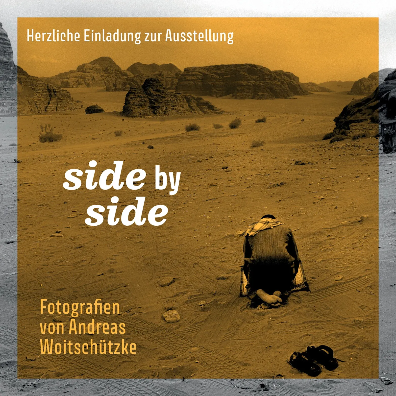 Einladung zur Ausstellung „side by side“, Fotografien von Andreas Woitschützke: Ein Mann kniet betend auf einer Matte im Wüstensand, dahinter Felsen und Weite, das Bild ockerfarben getönt. Aufgenommen im Wadi Rum, Jordanien, 2023.